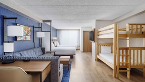 Una camera d'albergo moderna con un letto, una poltrona, una scrivania e una televisione.