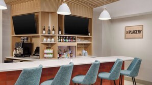 Angolo bar con un bancone bianco, sgabelli blu e scaffali pieni di bottiglie e bicchieri.