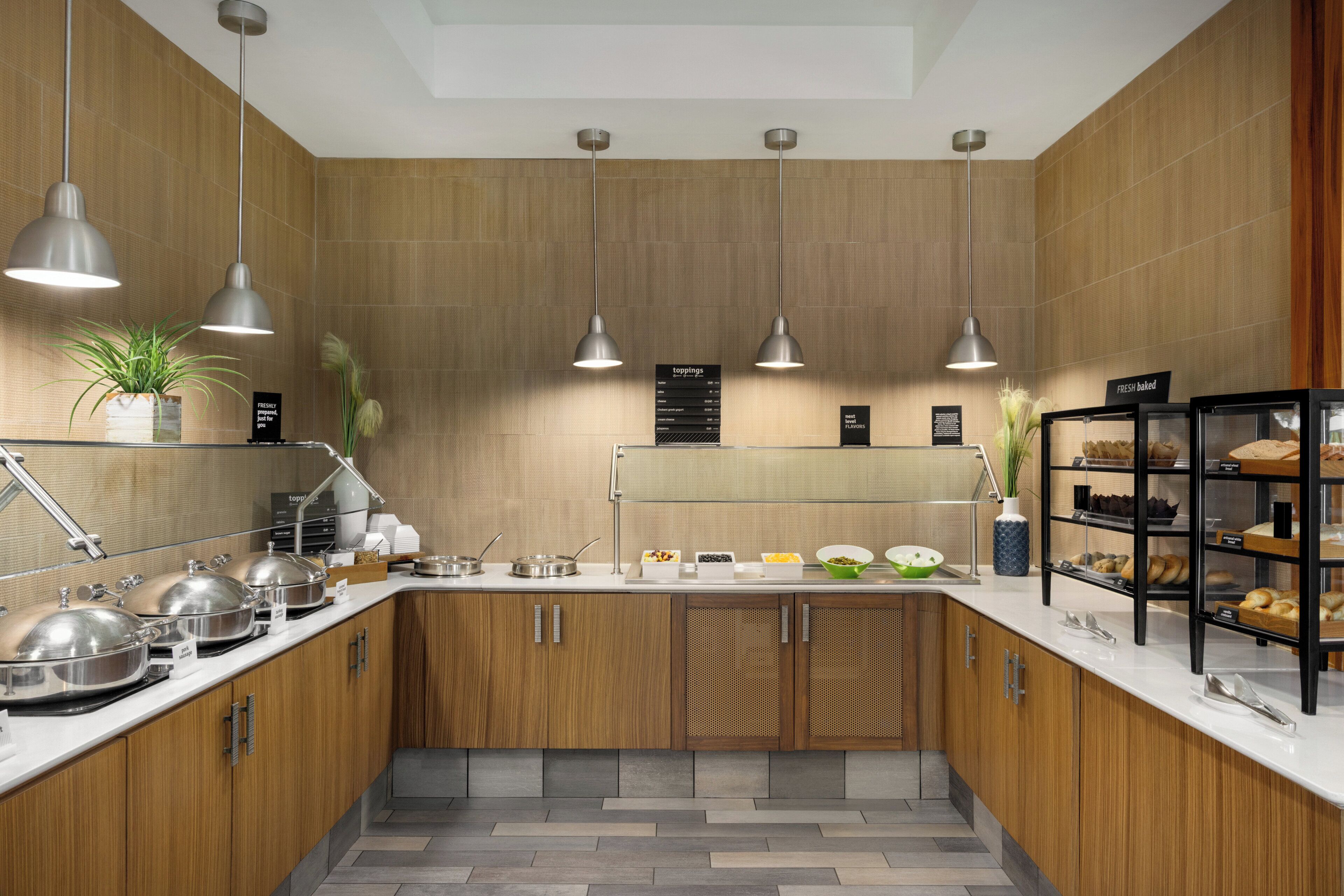 A modern kitchen with wooden cabinets, stainless steel appliances, and a variety of food items displayed on the counter.