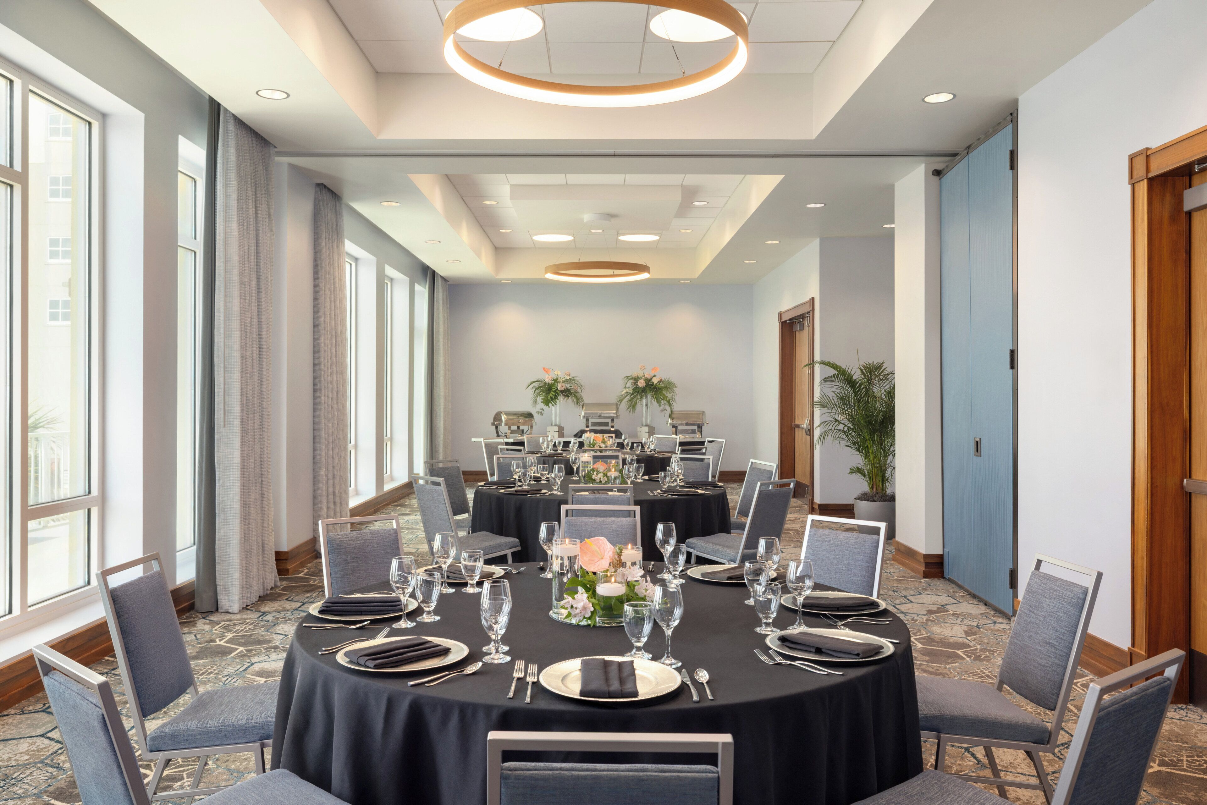 A conference room with round tables, chairs, and a floral centerpiece.