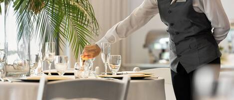 Una mesa de comedor bien dispuesta con una tarjeta de identificación, una planta en maceta y un camarero con uniforme.