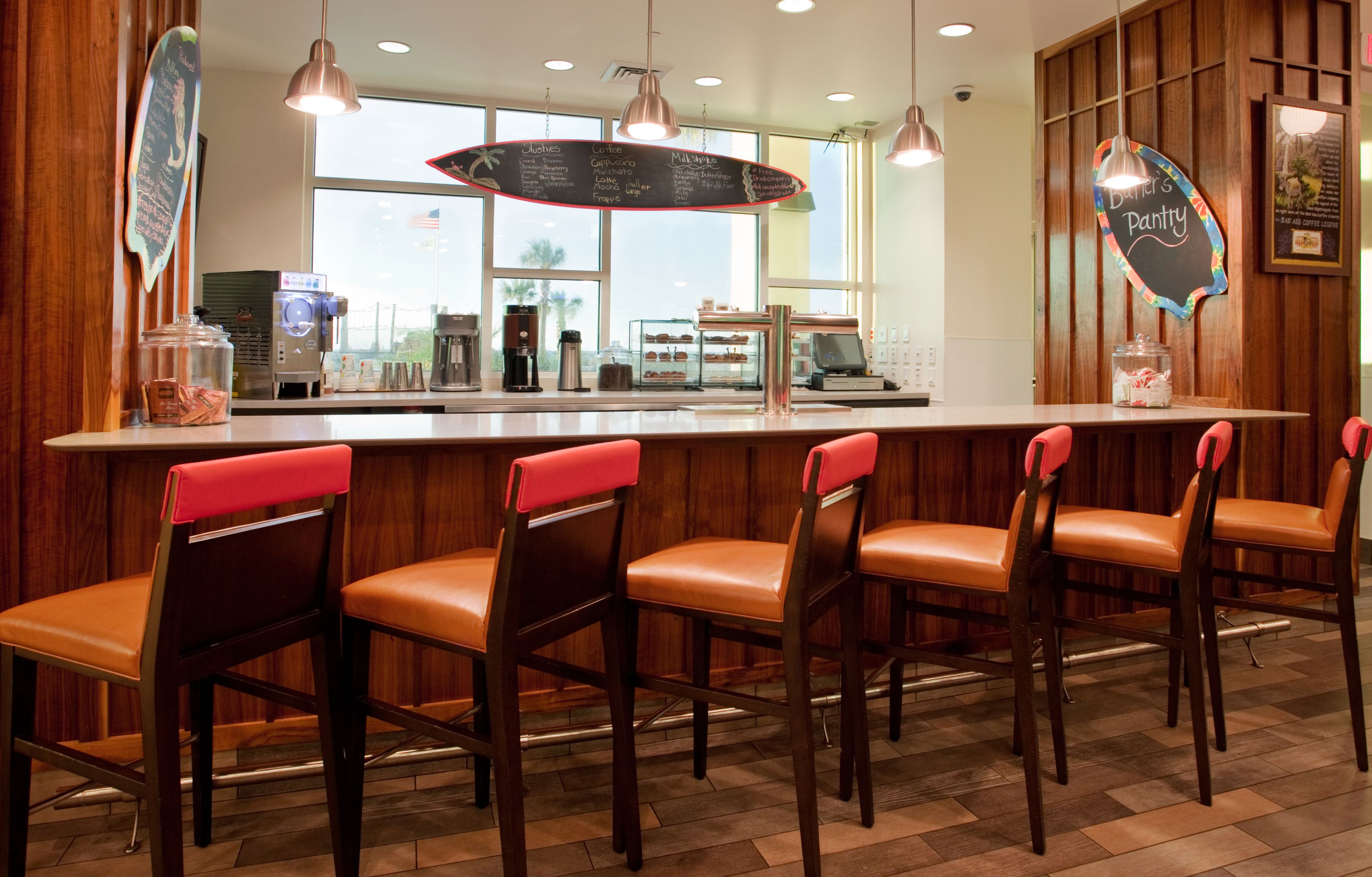 A bar area with wooden chairs and a counter, a chalkboard menu, and a coffee machine.