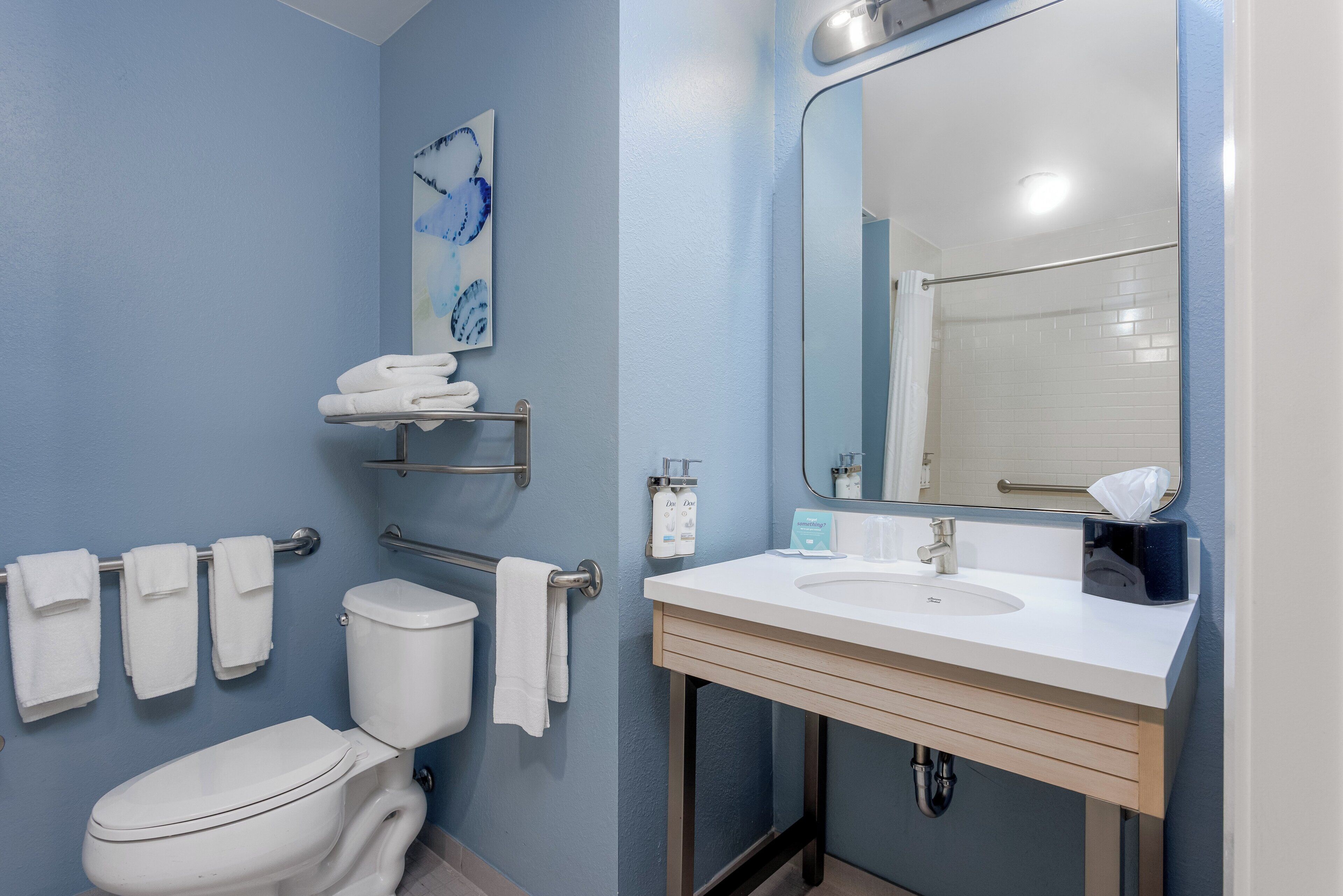 A bathroom with a white toilet, a sink with a mirror, and towels on a rack.