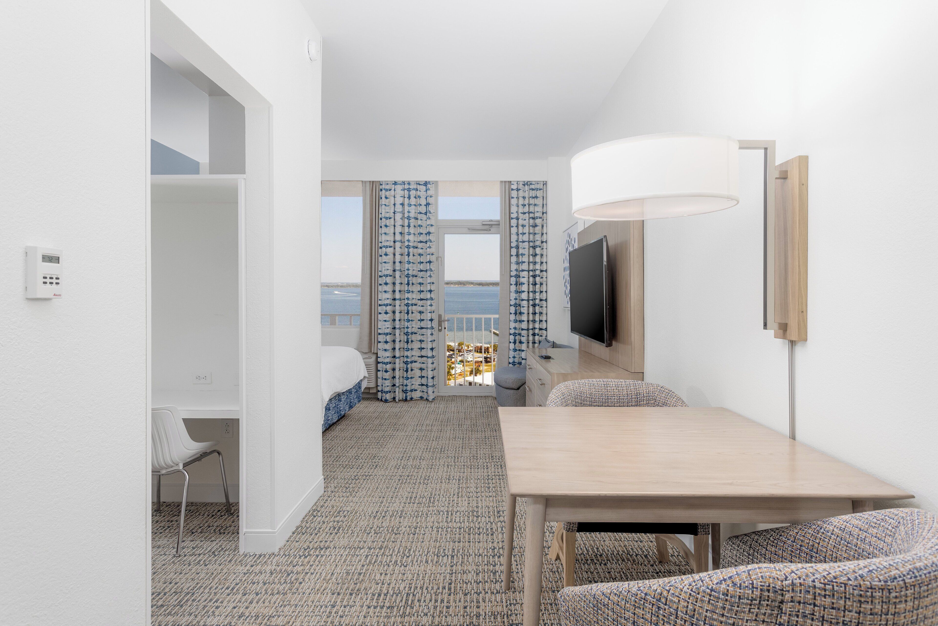 Ein Hotelzimmer mit Bett, Schreibtisch, Stuhl, Fernseher und Meerblick.