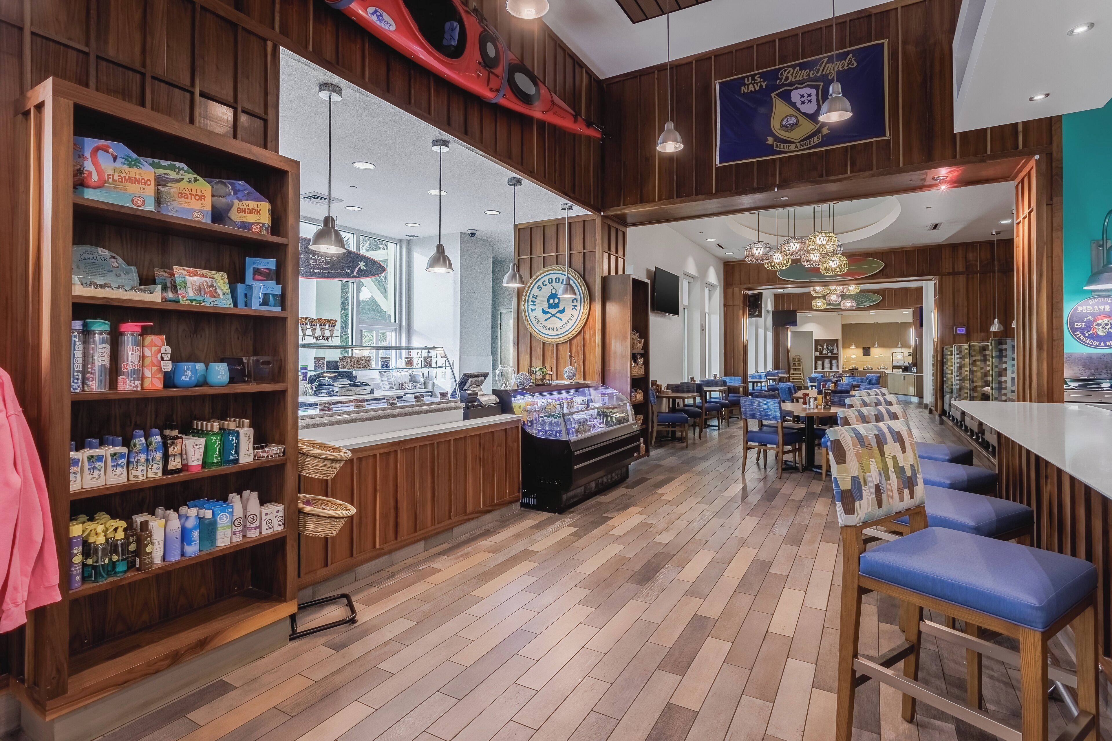 A nautical-themed restaurant interior with wooden paneling, a counter with a display case, and a seating area with blue cushioned chairs.