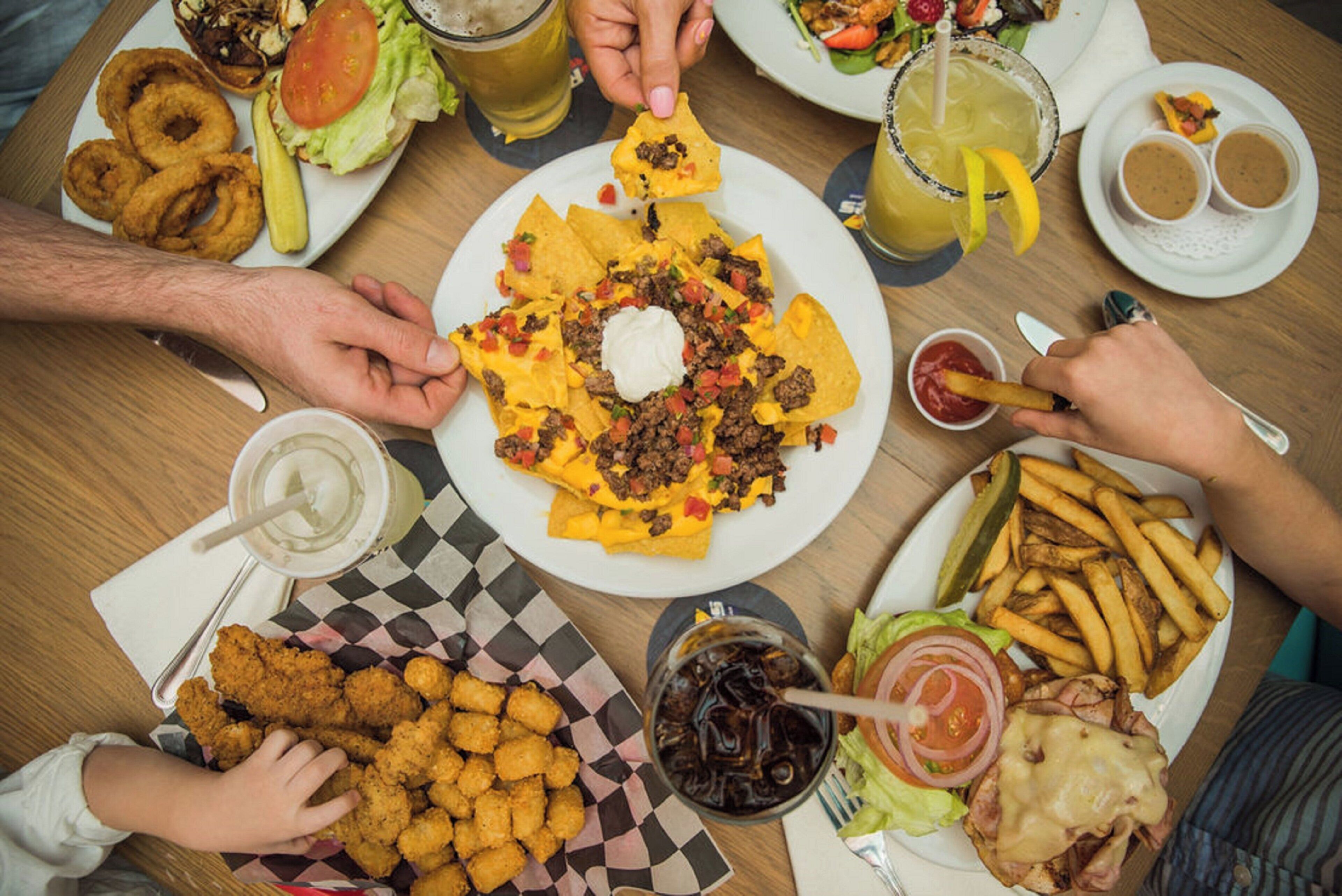 Ein Tisch mit verschiedenen Speisen, darunter Nachos, Pommes und Chicken Nuggets.