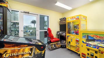 Una habitación con un juego de arcade de temática caribeña, una silla roja y un juego con temática de taxi amarillo.
