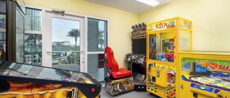 A room with a Caribbean-themed arcade game, a red chair, and a yellow taxi-themed game.