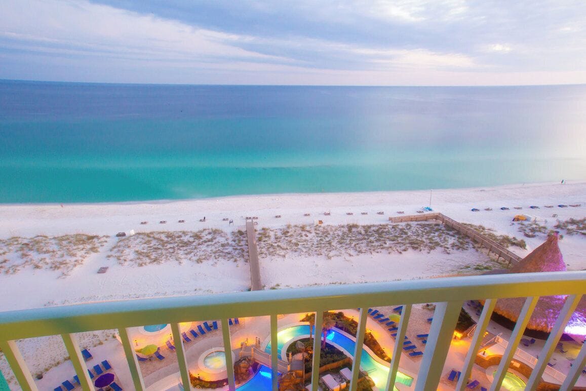 A beach resort with a pool area, lounge chairs, and a view of the ocean.