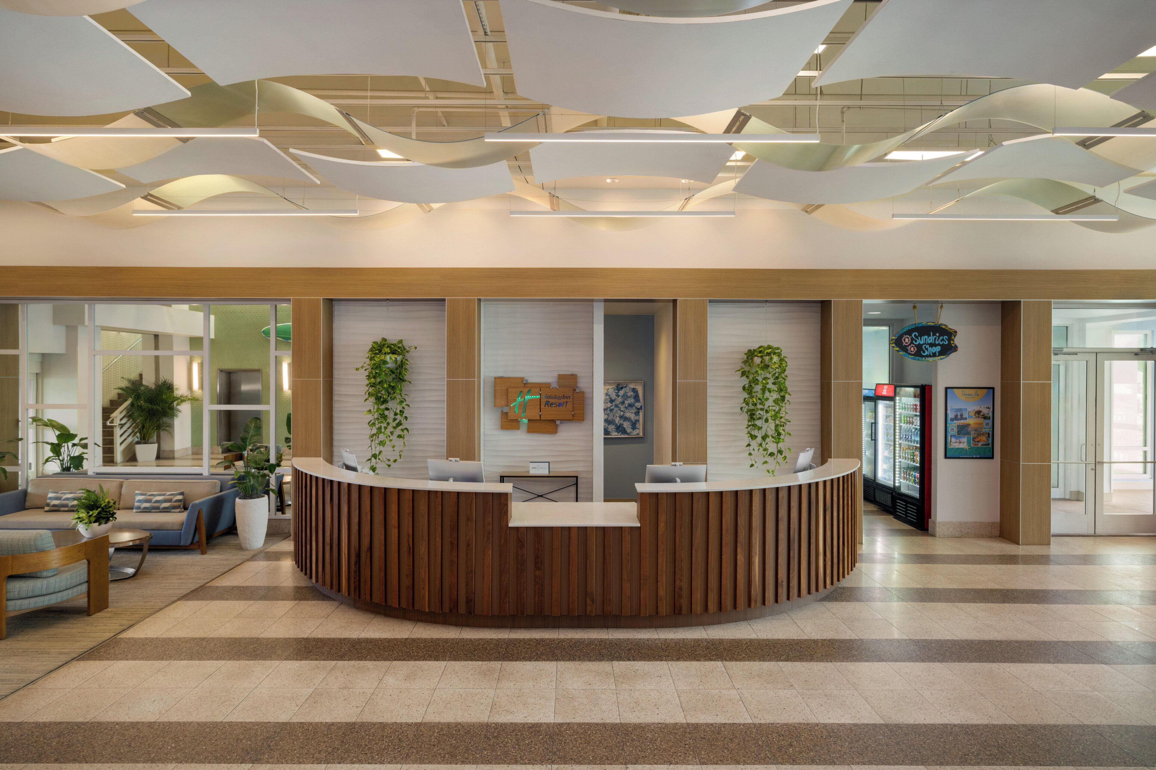A reception area with a wooden reception desk, potted plants, and a refrigerator.