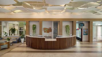 A reception area with a wooden reception desk, potted plants, and a refrigerator.