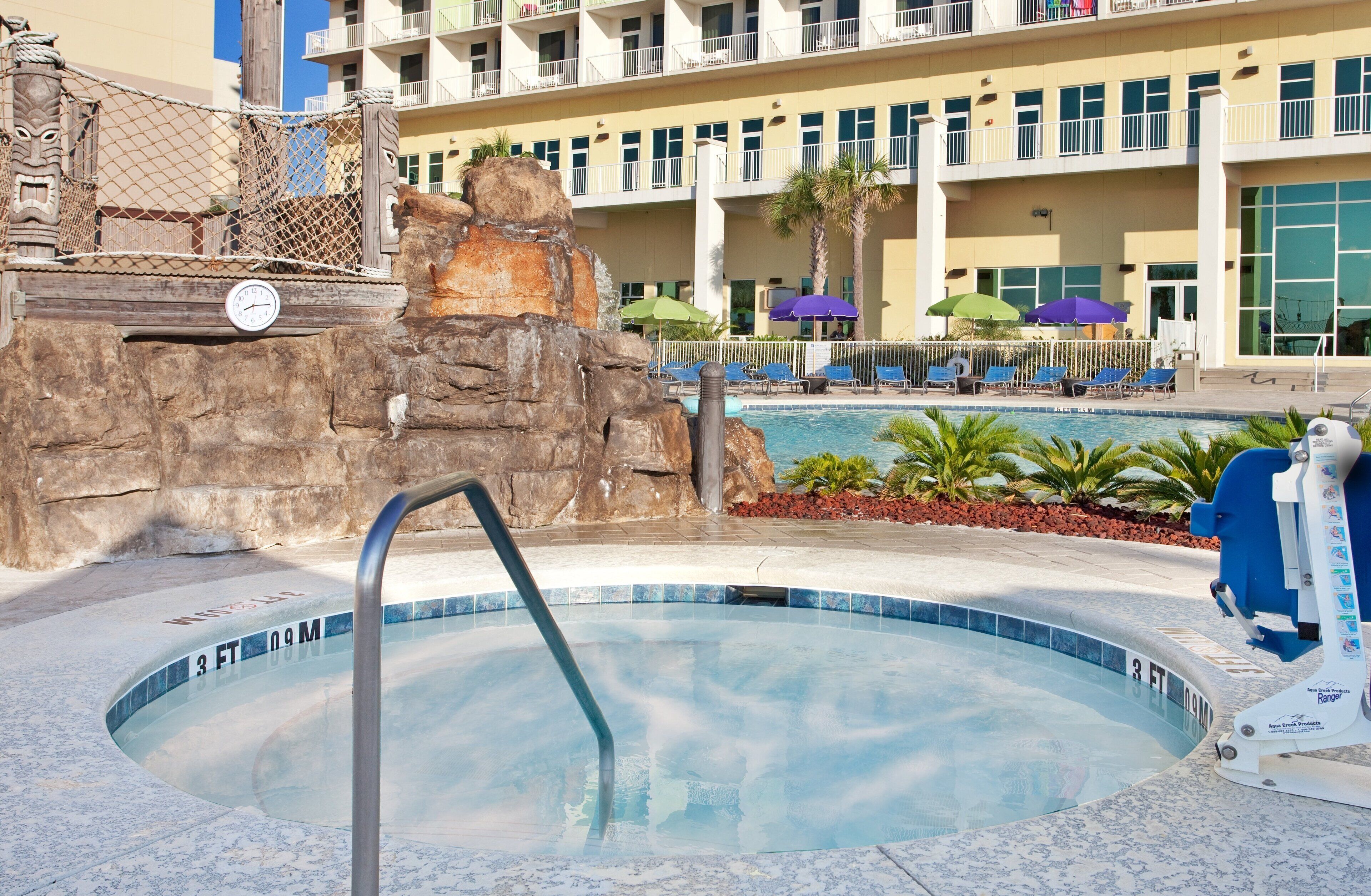 Ein Hotelpoolbereich mit Whirlpool, Liegestühlen und einer Palme.