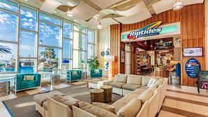 A spacious lobby with large windows, a Riptones Sports Grill, and comfortable seating areas. - Holiday Inn Resort Pensacola Beach by IHG (Pensacola Beach)