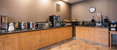 A kitchen with wooden cabinets, a clock, and various appliances like a refrigerator, microwave, and toaster.