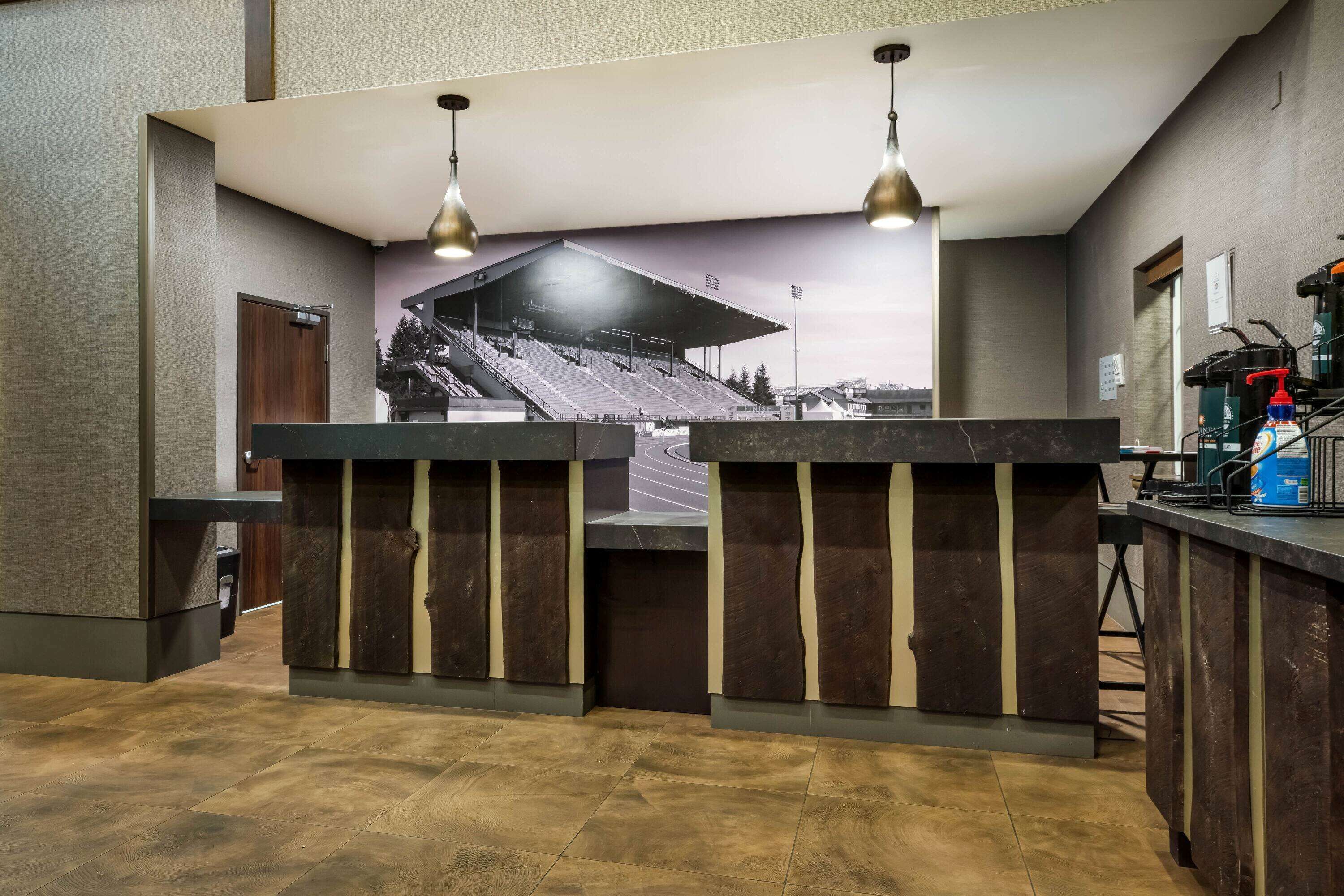 A reception area with a counter, two pendant lights, a large mural of a stadium, and a view of the outside.