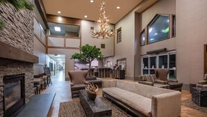 A spacious lobby with a fireplace, comfortable seating, a large chandelier, and a tree. - La Quinta Inn & Suites by Wyndham Eugene (Eugene)