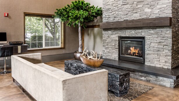 A modern living room with a stone fireplace, a large window, and a cozy seating area. - La Quinta Inn & Suites by Wyndham Eugene (Eugene)