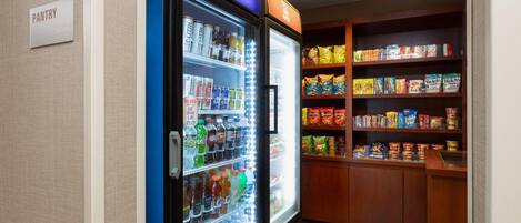 Eine Speisekammer mit einem Pepsi-Kühlschrank, gefüllt mit Getränken und Snacks.