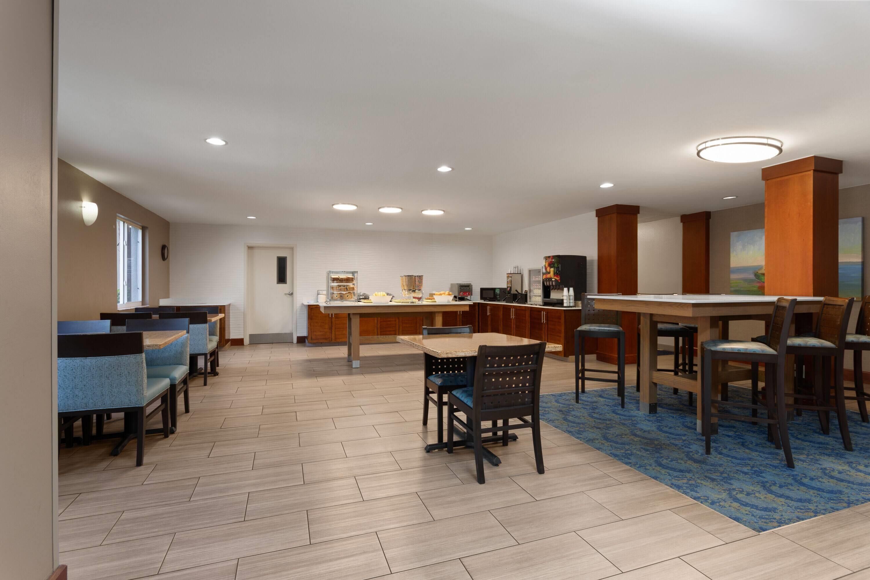 A hotel dining area with multiple seating options, including booths and tables, and a central bar area.