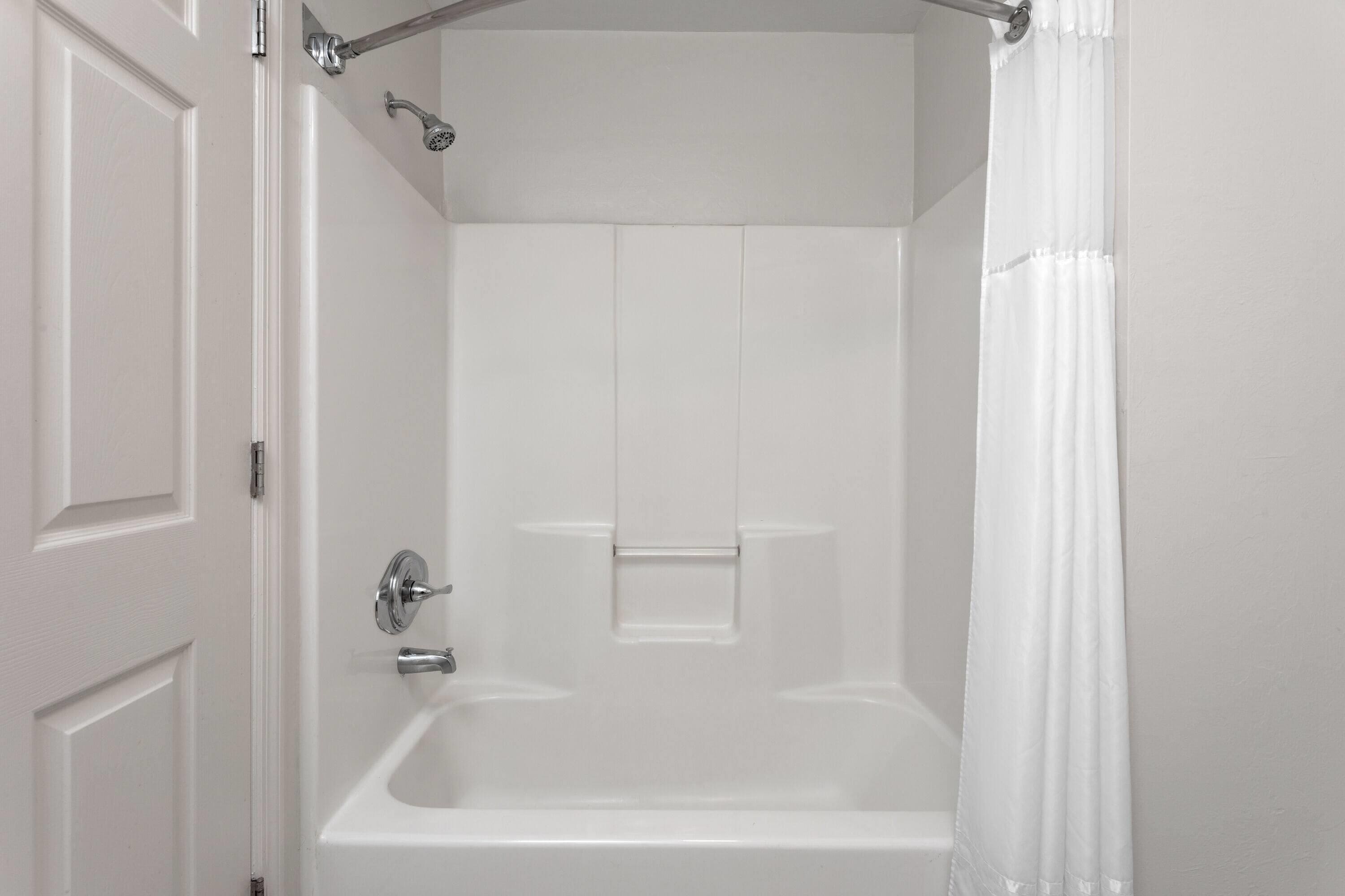 Un baño blanco con bañera, ducha y puerta.