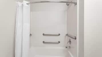Una bañera blanca con dos barras de apoyo y una cortina de ducha.