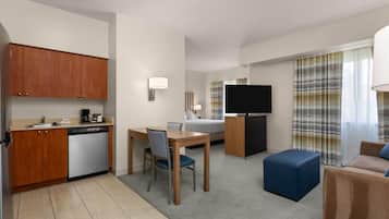 Quarto de hotel compacto com cozinha compacta, área de refeições, cama, televisão e espaço para sentar.