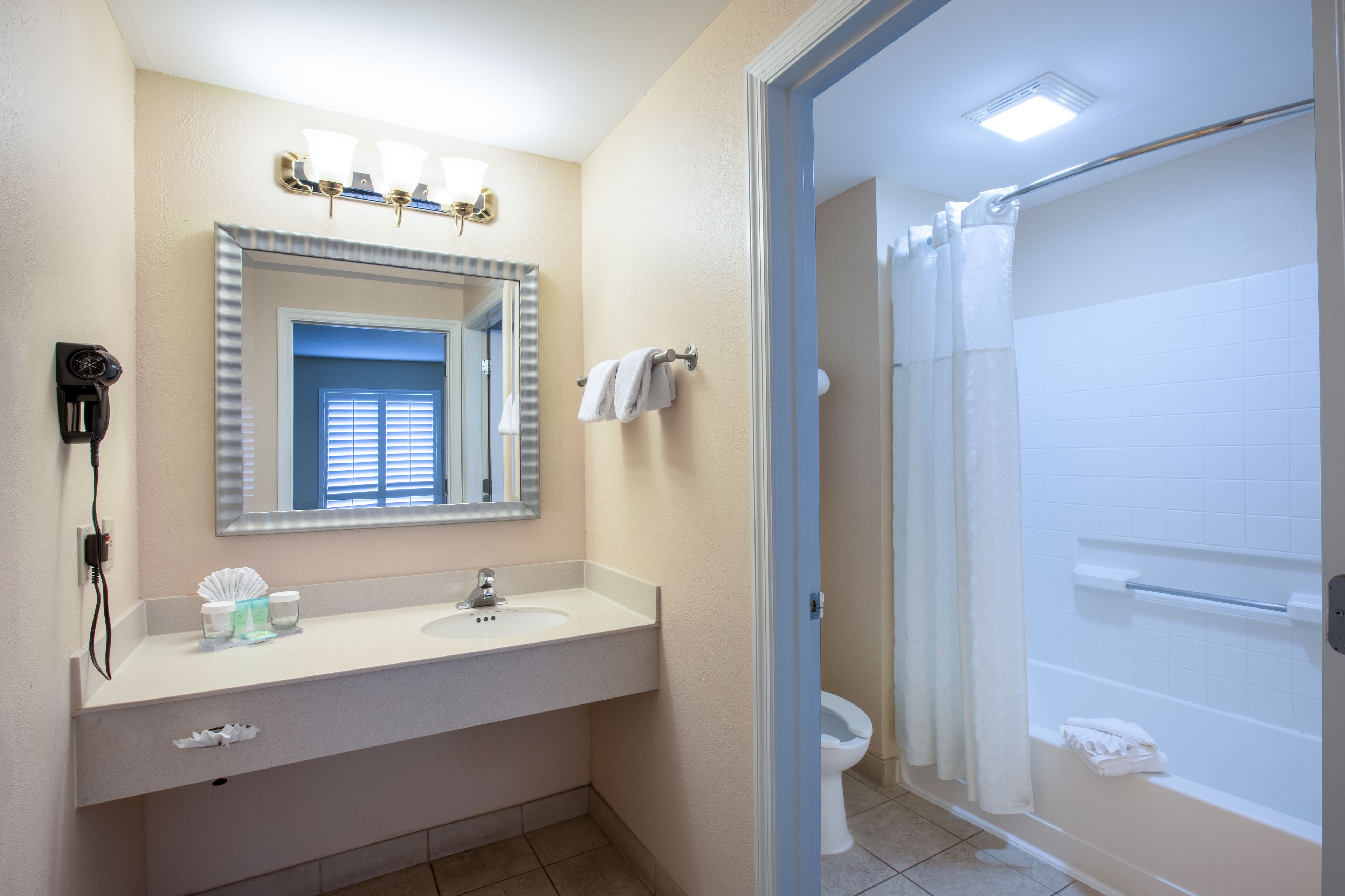 Un baño con lavamanos, espejo y ducha.