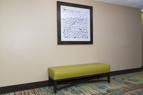 A framed abstract artwork on a wall, a bench, and a patterned carpet.