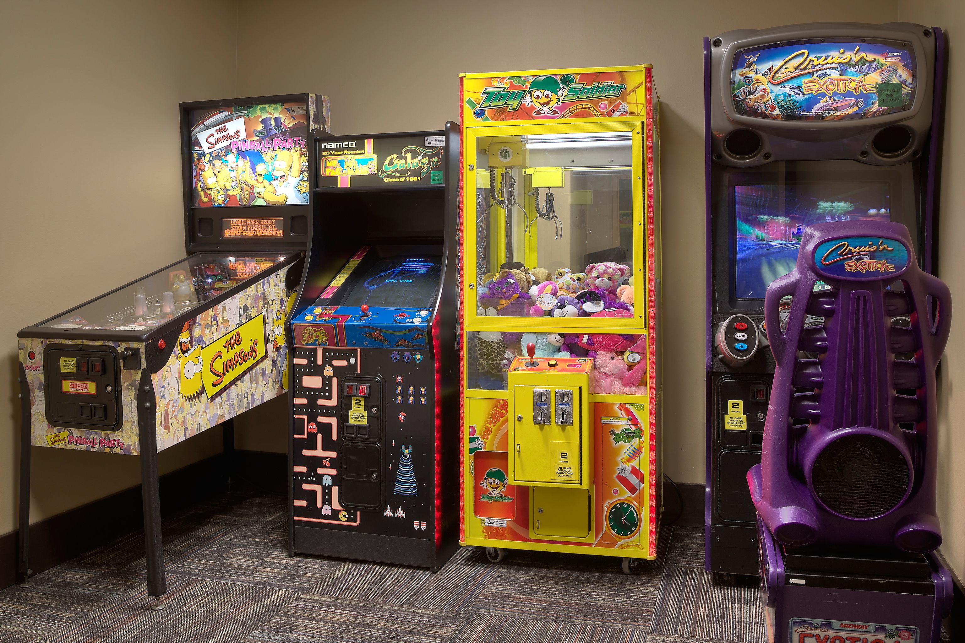A row of arcade machines including 'The Simpsons' and 'Toy Story' games.