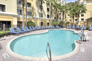 A swimming pool with lounge chairs and palm trees.
