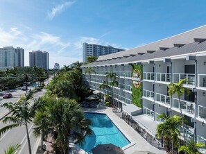 A hotel with a pool, palm trees, and a city skyline in the background. - The Garden Hotel & Resort (Fort Lauderdale)
