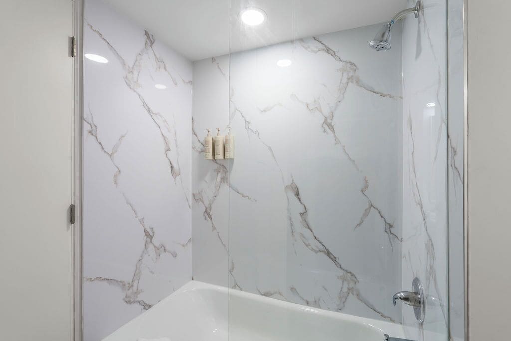 Une salle de bain moderne avec une douche à parois de verre et un mur en marbre.