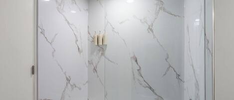Une salle de bain moderne avec une douche à parois de verre et un mur en marbre.