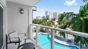 A balcony with a pool, white walls, and a view of high-rise buildings.