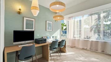 A modern room with a wooden desk, two chairs, a computer, and wall-mounted lamps.
