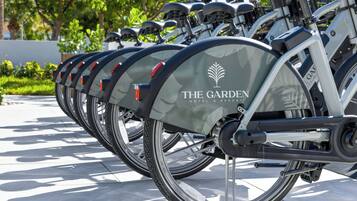 Una hilera de bicicletas con la marca 'The Garden' estacionadas sobre una superficie de baldosas.