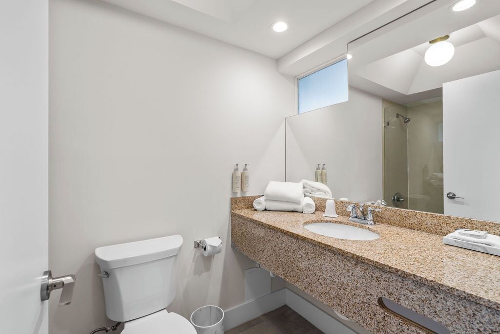 A modern bathroom with a toilet, sink, and shower.