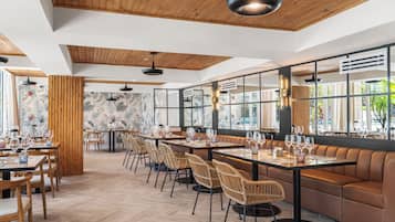 A restaurant with wooden ceiling, large windows, and a mix of wooden and upholstered seating.
