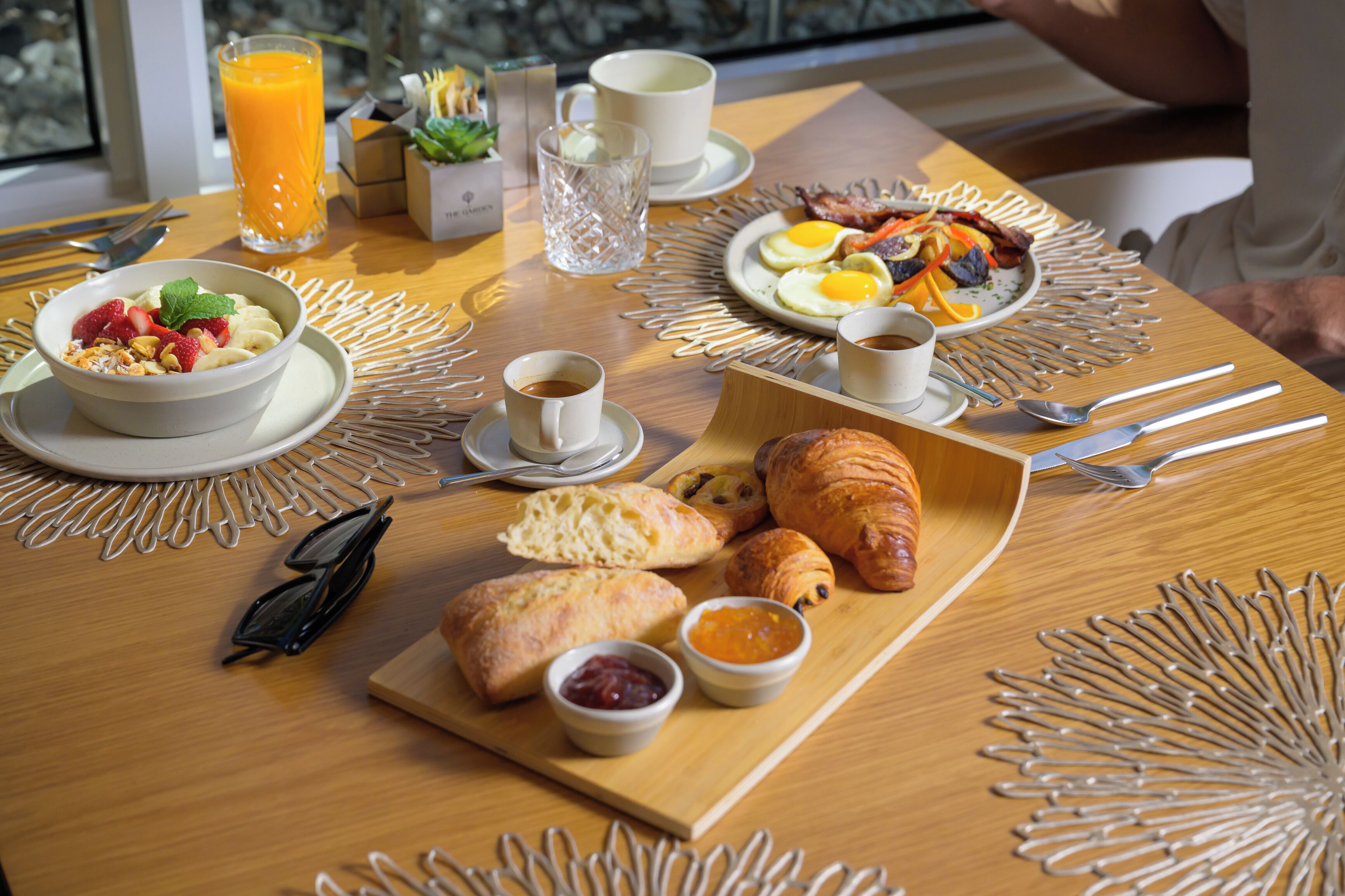 A breakfast table with croissants, eggs, and a bowl of fruit.