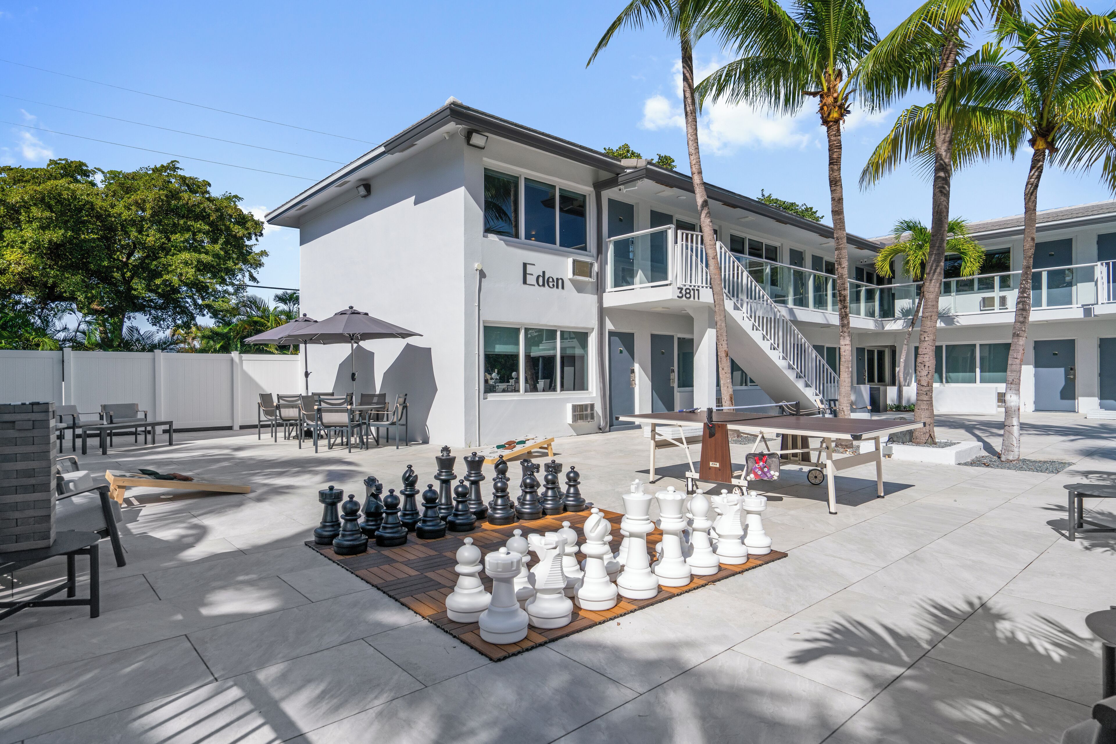 A modern building with a nameplate 'Eden' and a chessboard setup on the patio.