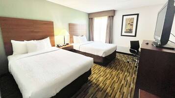 A hotel room with two beds, a desk with a computer, a chair, and a television.
