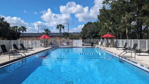 A rectangular swimming pool with a white deck, surrounded by lounge chairs and umbrellas. - Quality Inn Gainesville I-75 (Gainesville)