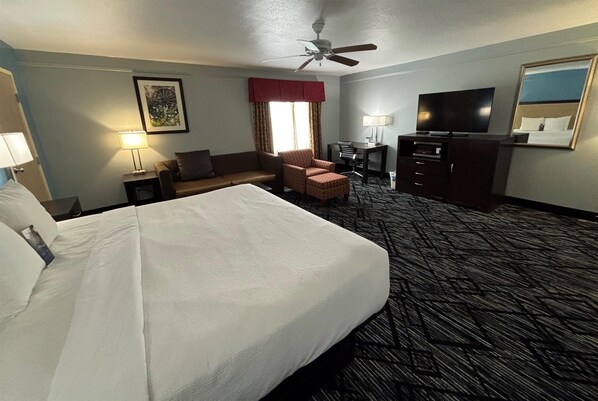Habitación de hotel con una cama grande, un escritorio, una silla, un televisor y un ventilador de techo.