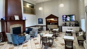 A restaurant with a fireplace, seating area, and a television. - Baymont by Wyndham Litchfield (Litchfield)