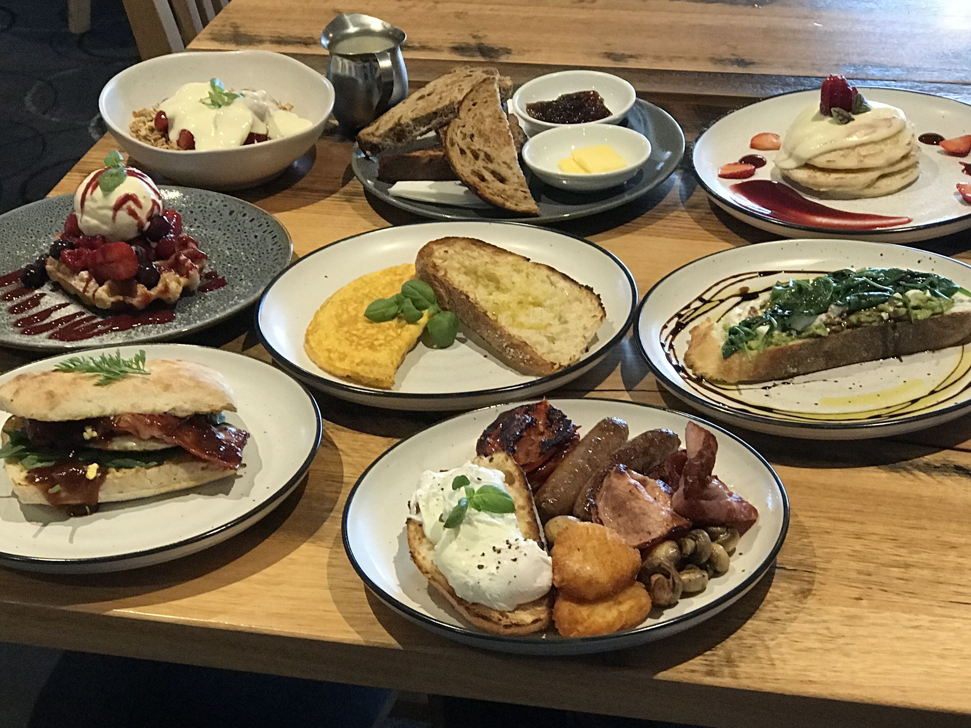 A variety of breakfast dishes on a wooden table.
