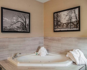 Bathroom features a bathtub, framed photographs, and light-colored tiles.