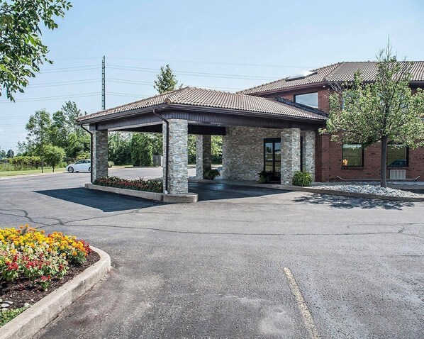 A building with a covered entrance, stone pillars, and a brick facade.