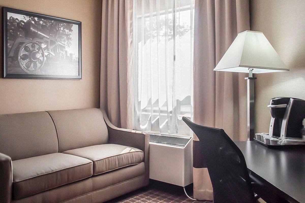 Relax in this cozy space with a sofa, desk, and coffee maker.