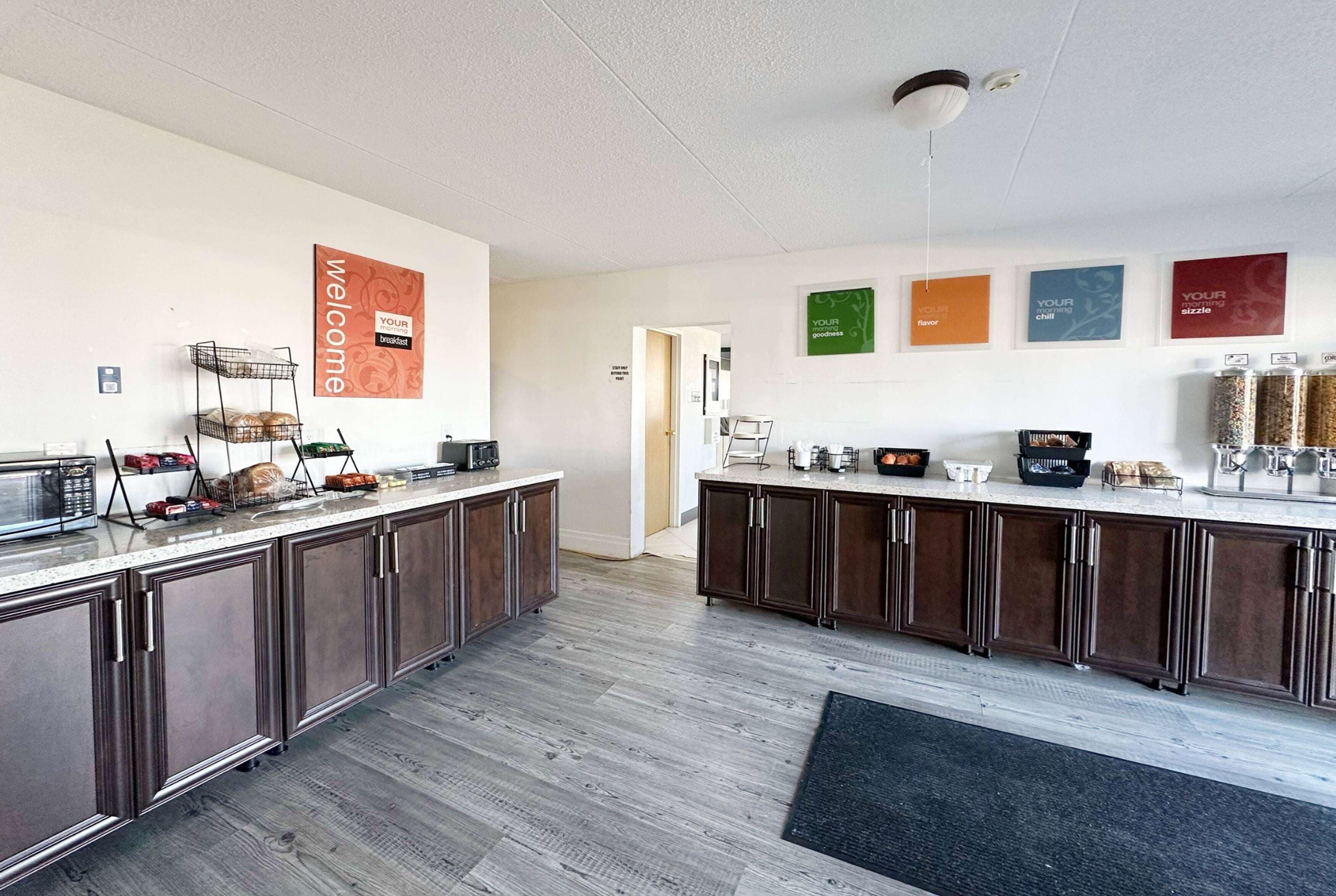 Eine moderne Küche mit dunklen Holzausziehtüren, einer Arbeitsplatte aus Granit und einem schwarzen Teppich. Auf der Arbeitsplatte befinden sich verschiedene Küchengeräte und eine Kaffeemaschine.