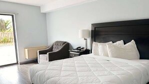 Ett hotellrum med en stor säng, en stol, ett nattduksbord och en lampa.
